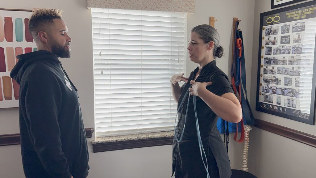 A woman explains something to a man in an office, gesturing with her hands while the man listens attentively.