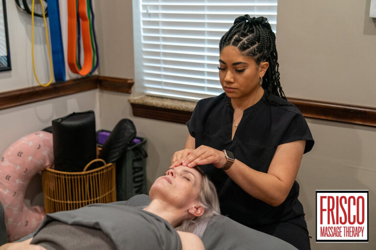 A massage therapist performs a facial massage on a client lying on a table in a treatment room at Frisco Massage Therapy, sharing tips on how to prepare for manual lymphatic drainage.