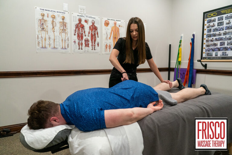 A massage therapist works on a client lying face down on a table in a treatment room with anatomical charts and visible cupping marks. Text in the corner reads "Frisco Massage Therapy.