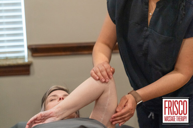 A massage therapist stretches a client's arm while the client lies on a table at Frisco Massage Therapy, offering specialized massage therapy for scar pain.