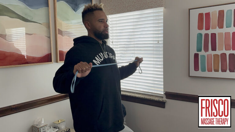 A man stands indoors using a resistance band for exercise in a room decorated with abstract art. A "Frisco Massage Therapy" logo appears in the lower right corner, highlighting the benefits of sports massage for injury prevention.